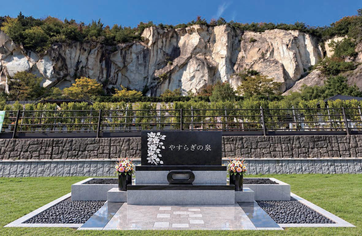 竜山の岩肌を背にした、「やすらぎの泉」と刻まれた黒御影石の供養墓